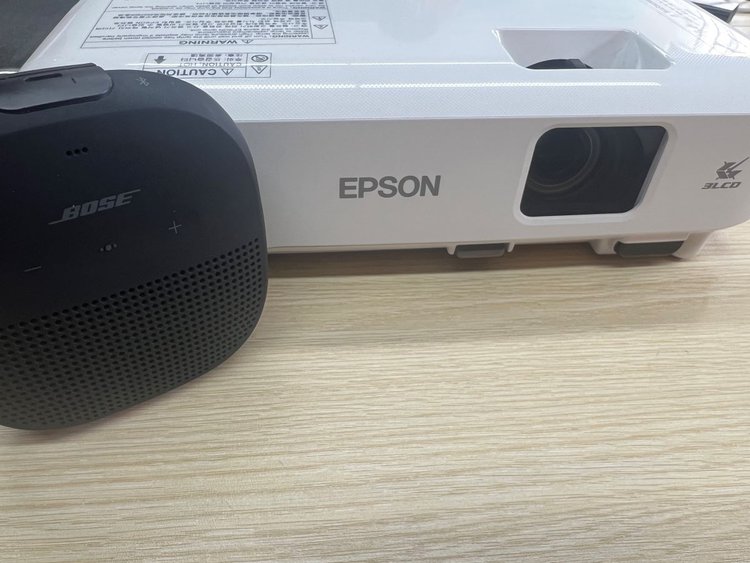 Bose speaker standing with Epson projector on a table