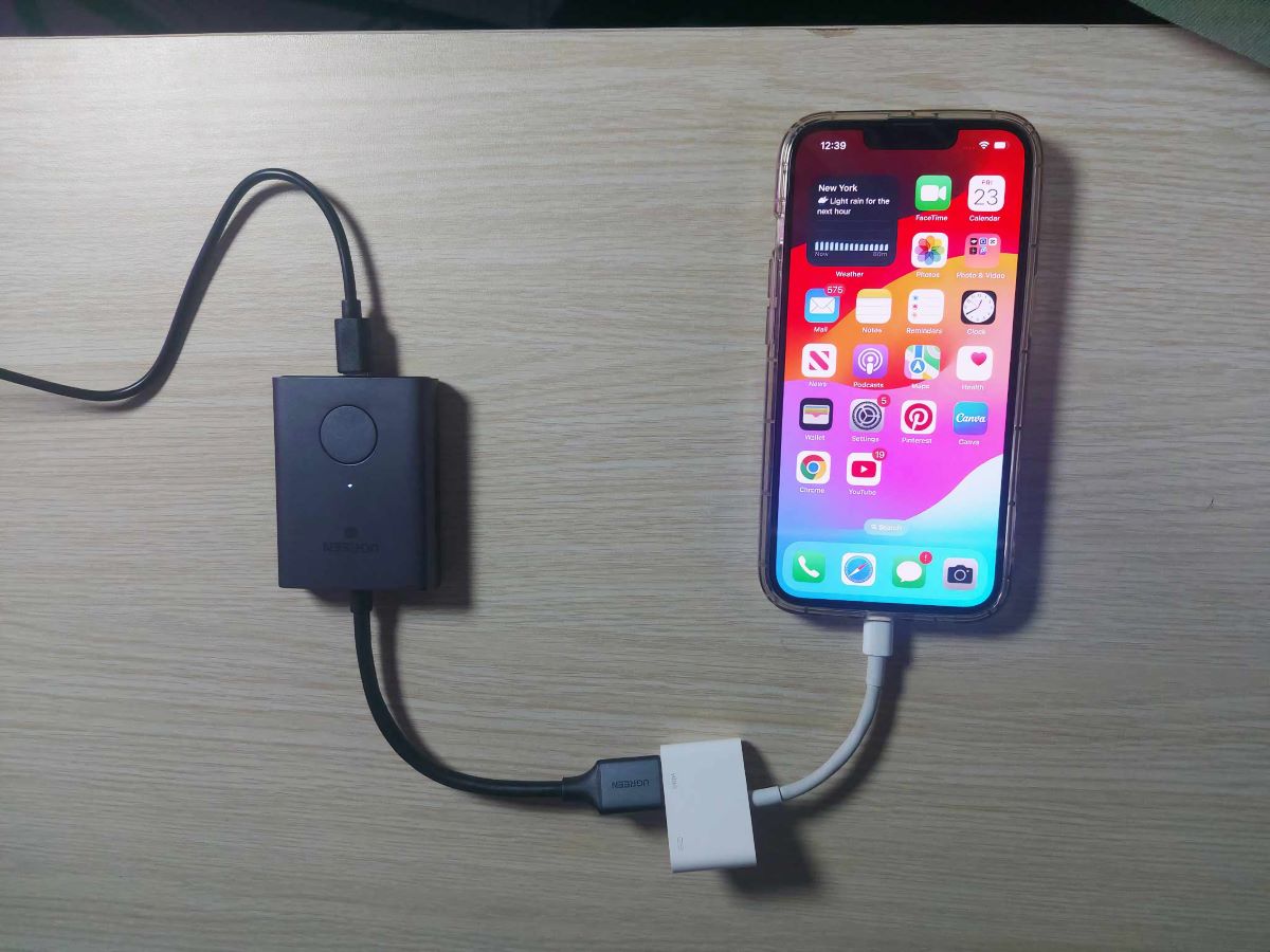 an iPhone 13 Pro Max is connected with an HDMI to lighting adapter and connected to HDMI transmitter
