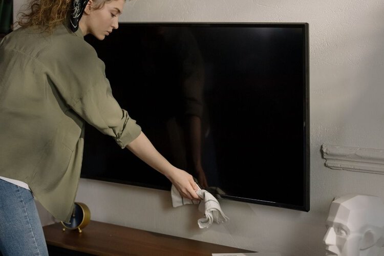 eine Frau, die den OLED-Fernseher reinigt