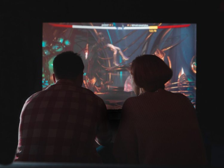 man and woman are play game on a black projector screen in low ambient light