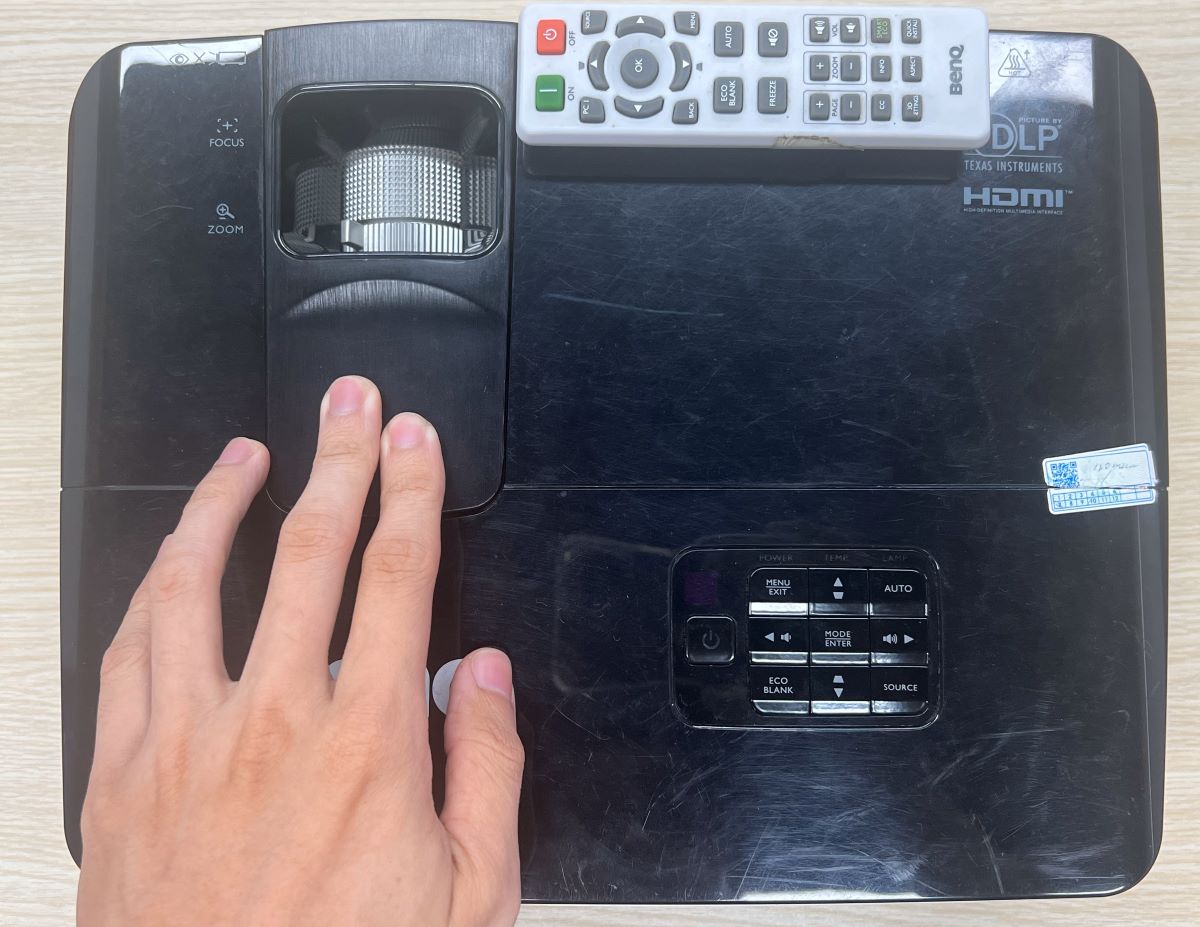 a hand holding down on a benq projector cover