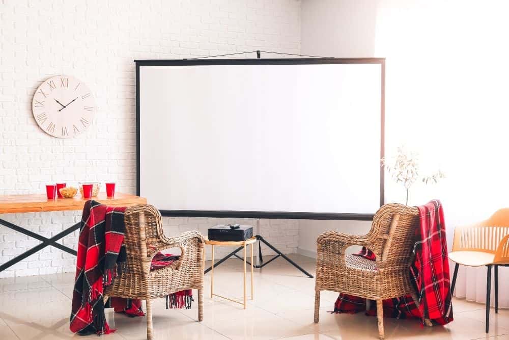 a projector on a short table in a living room with standard projector screen in a room
