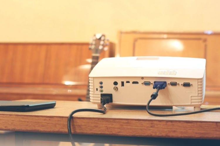 a projector on a table with VGA cable plugged in