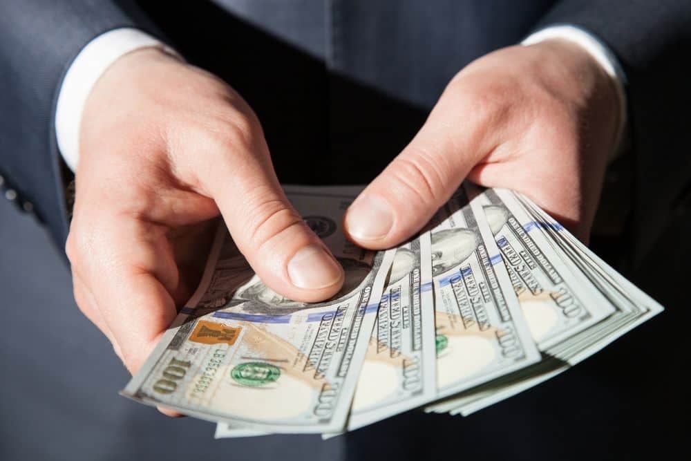 man's hands holding dollars