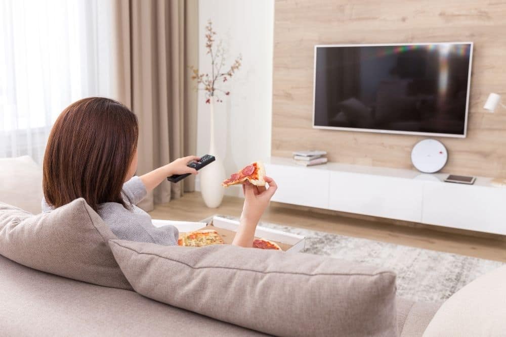 woman eating pizza and watching TV
