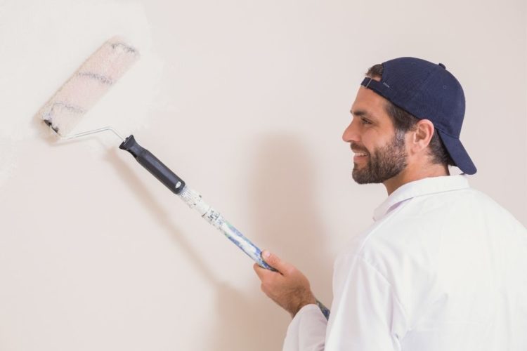 a man smiling and painting the wall projector screen white