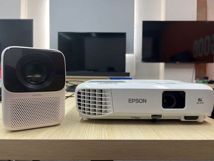 Wanbo projector standing next to Epson projector on the table