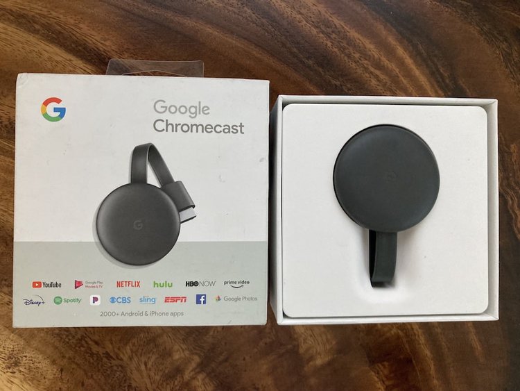 A black google chromecast with its box