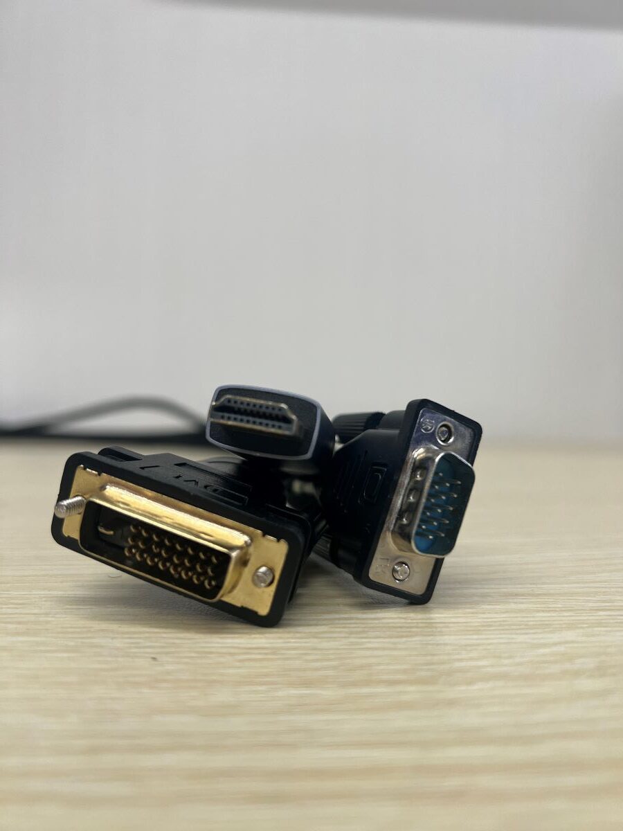 an HDMI cable and a DVI cable and a VGA cable all together on a wooden table with a white background