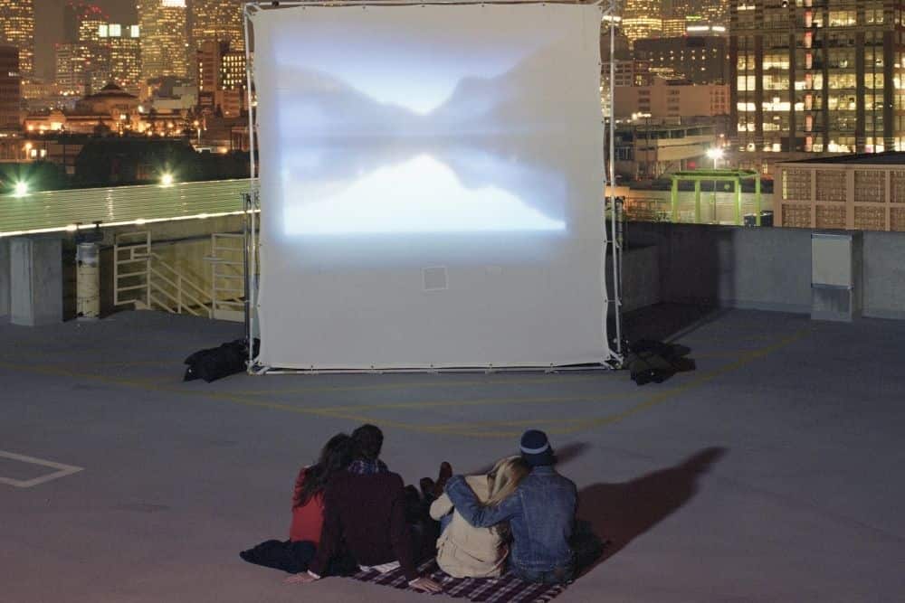 a group of friends using rear projector screens for movie night outdoor on a rooftop