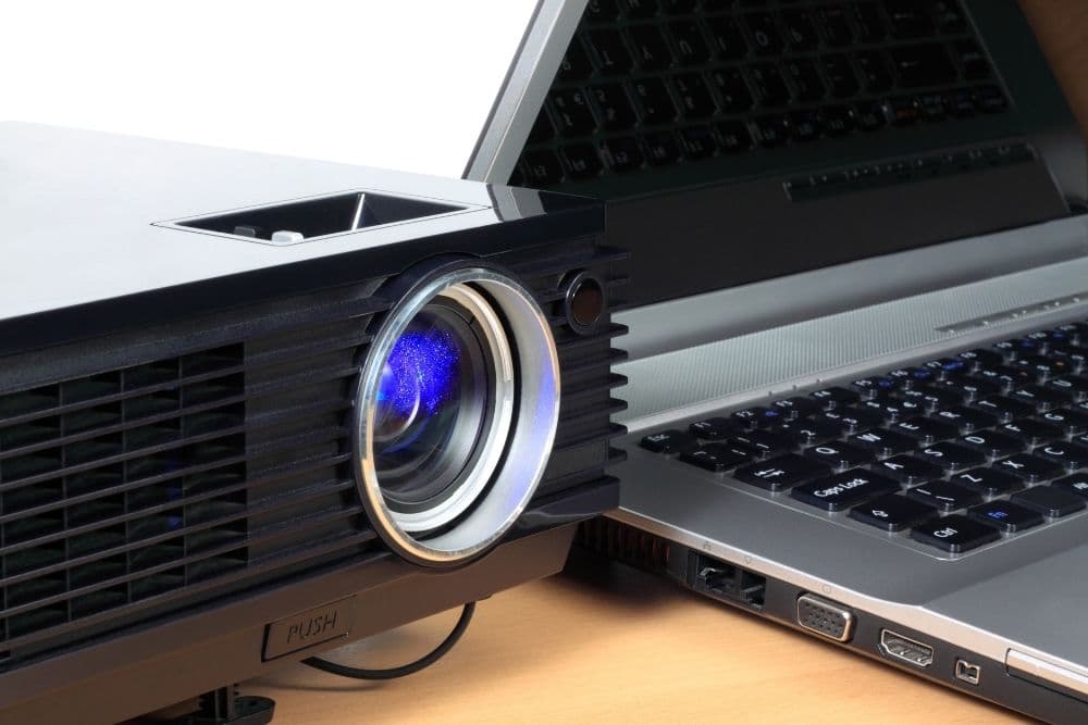 Ein Laptop, der neben einem schwarzen Projektor Wärme erzeugt