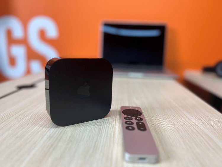 Apple TV and the remote with a macbook behind