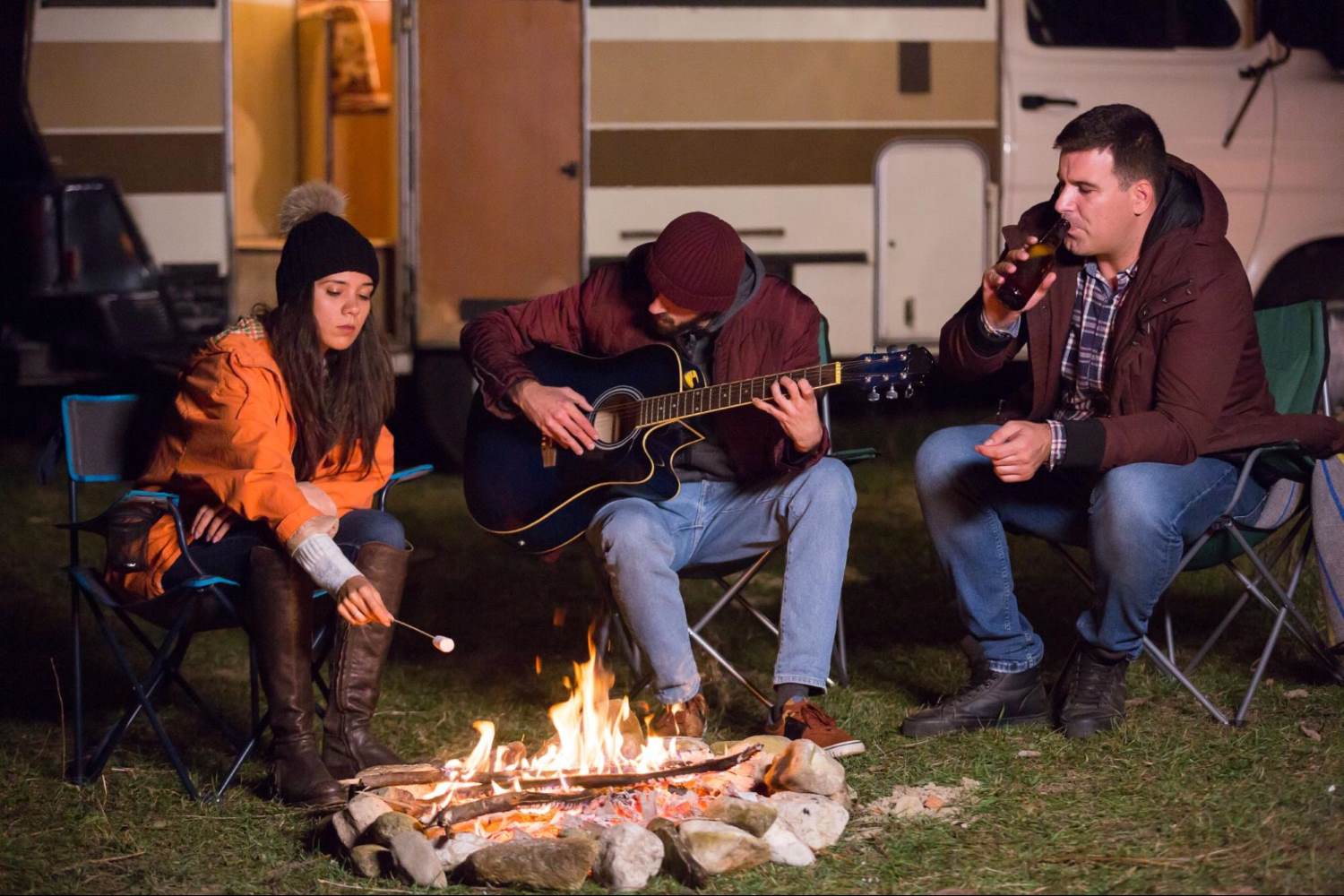 3 persons gathering around a campfire
