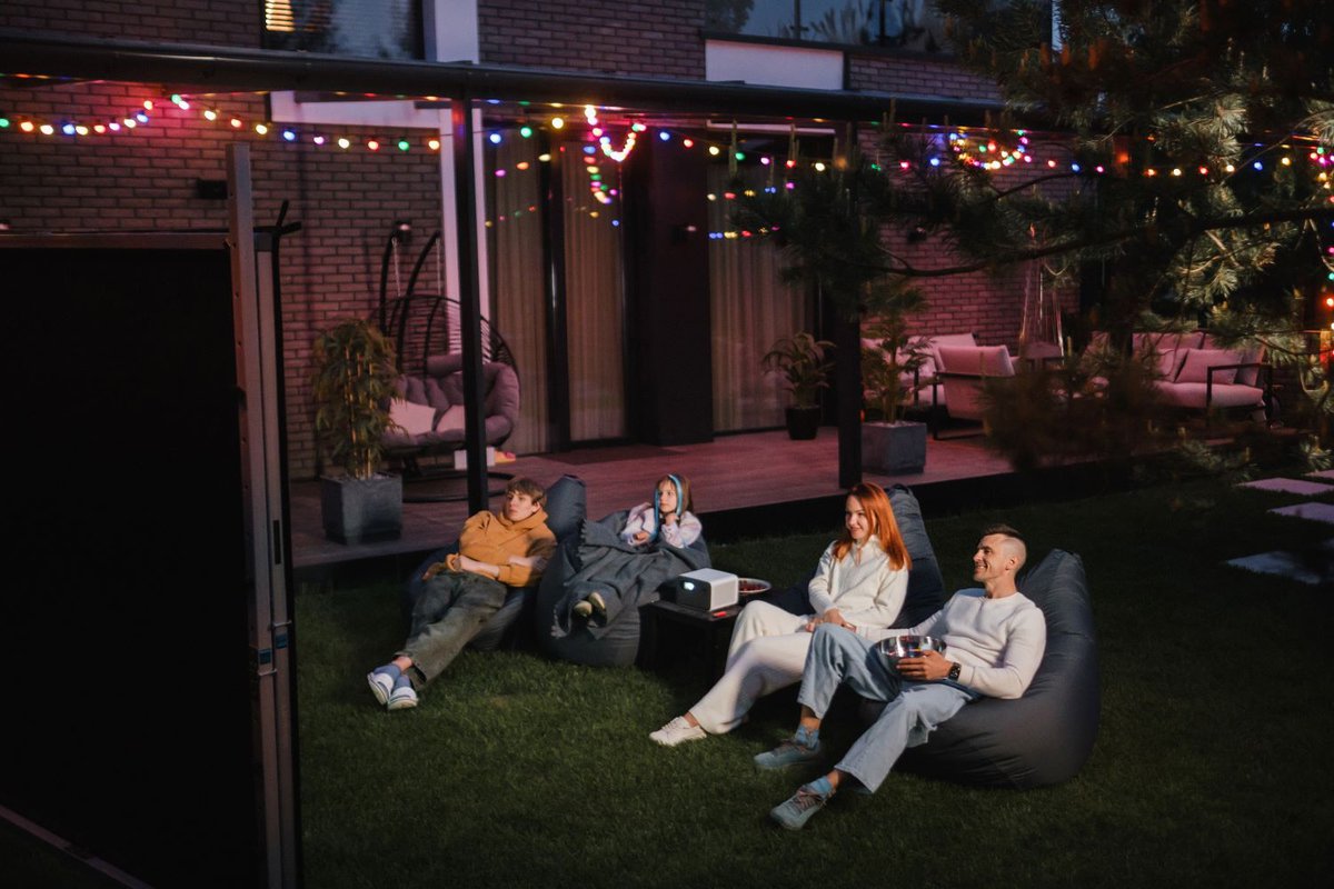 Family watching movies together with a backyard projector setup