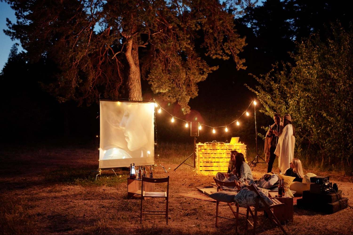 a group of people and a projector setup in the woods