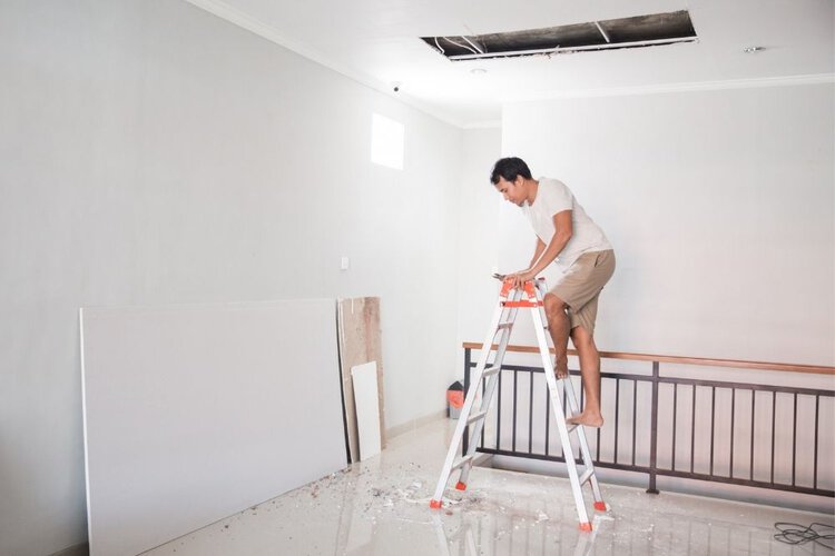 a man installing a holder onto the ceiling