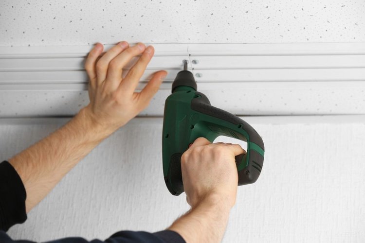 a man using a drill on the ceiling