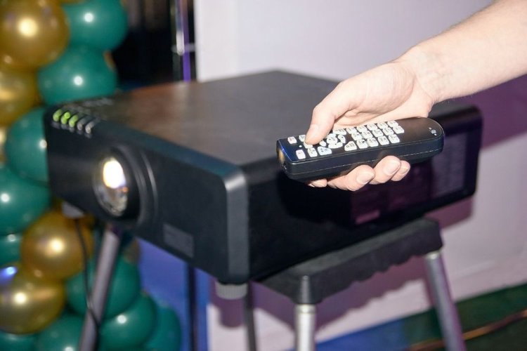 man adjusting projector color via a remote control