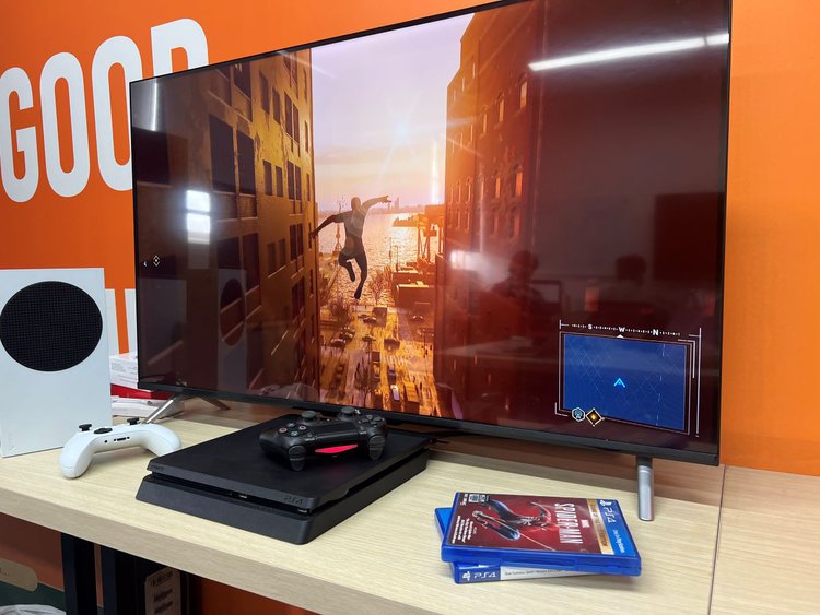 Spider-man game on TCL TV with PS4 and Xbox S on the Table