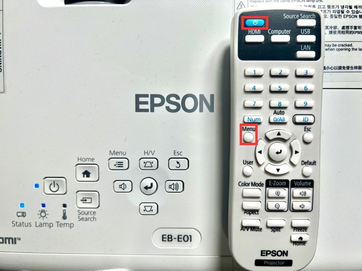 power and menu buttons on an epson remote are highlighted, the remote is on the top of the projector