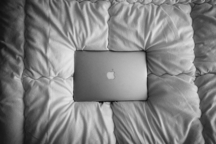 A Macbook on a white bed