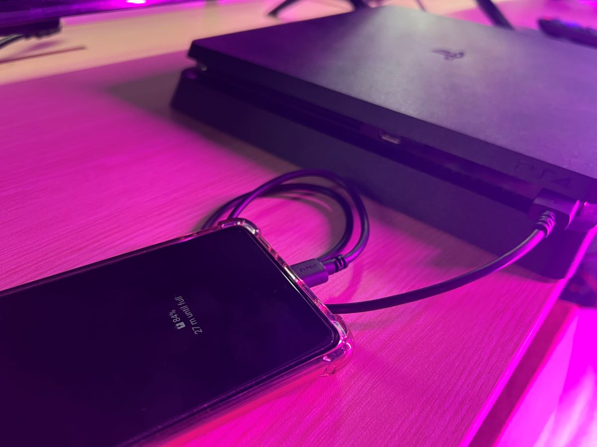 A Samsung phone is getting charged by the PS4 console via the USB port