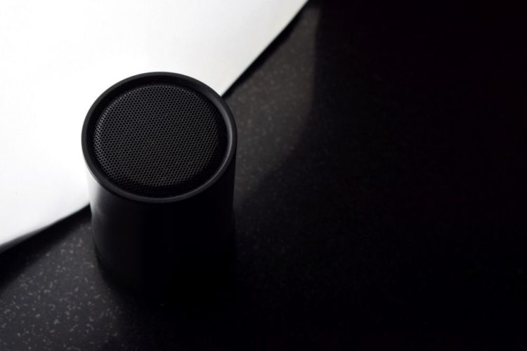 A black bluetooth speaker on a black and white table