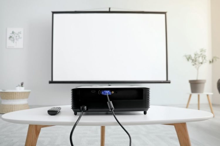 A black projector and a projector screen in a living room