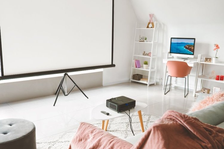 A cosy living room with a projector, a projector screen and a desktop
