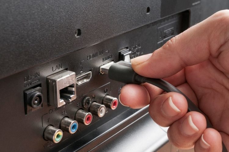 A man plugging an hdmi cable into a TV port