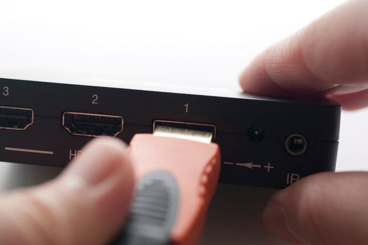 A man plugs a red hdmi cable into a port