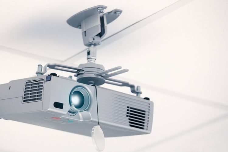 A white projector on a ceiling mount