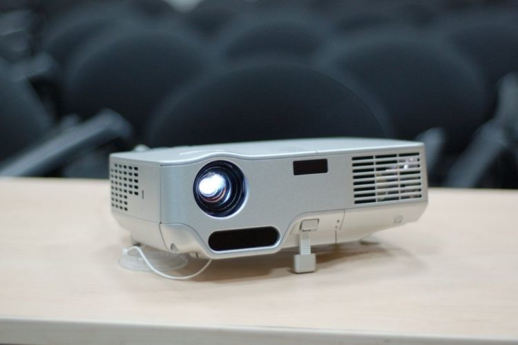 A white projector on a wood table