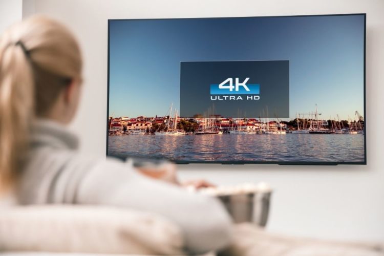 A woman watching a TV with 4K