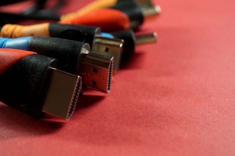 Different color HDMI cables on a red table
