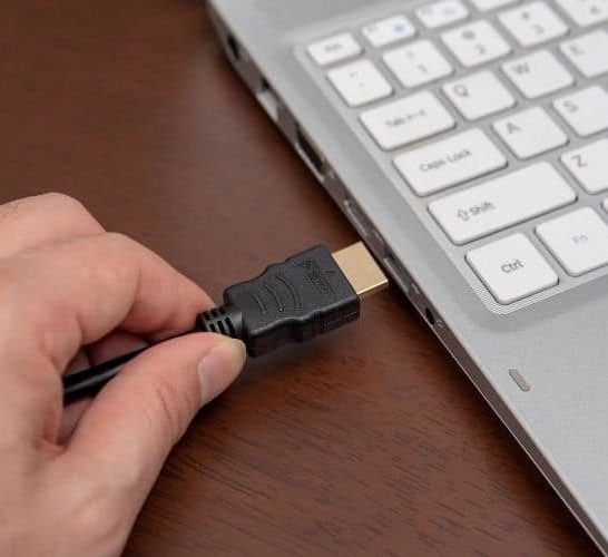 Man plug HDMI cable into laptop