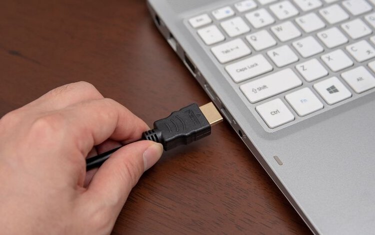 Man plug HDMI cable into laptop