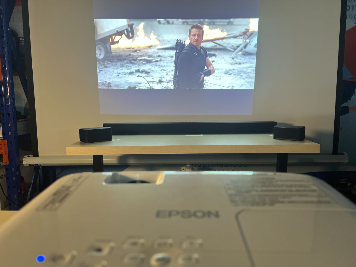 The Epson projector is connected to Vizio sound bar via Bluetooth with Vizio speakers are on a wooden table