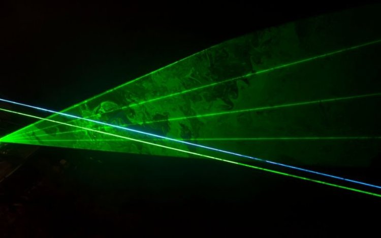Green laser beam on black background