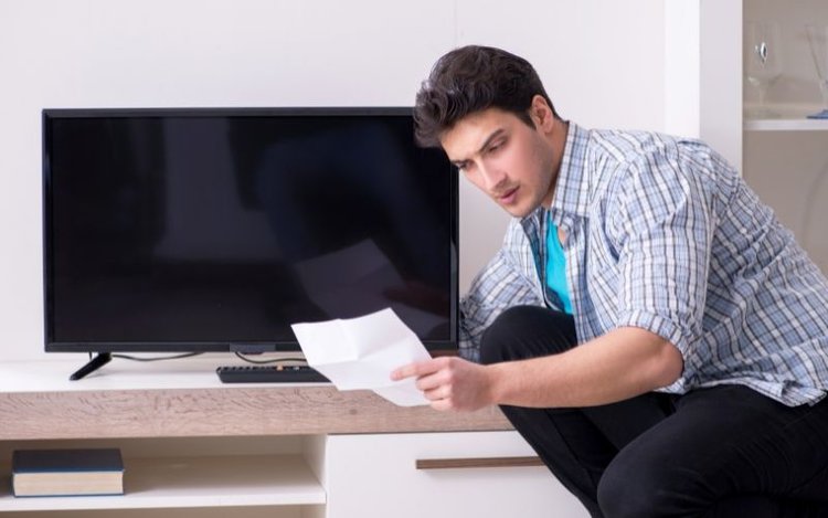 Man reading user manual and checking TV