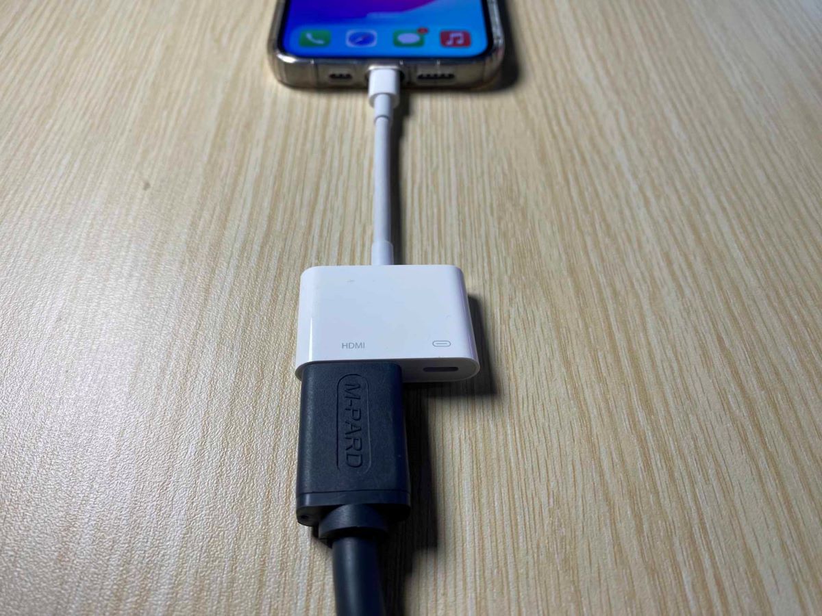 an iPhone 13 Pro is connected to Lightning to HDMI adapter and an HDMI cable is plugged to the HDMI port of the adapter