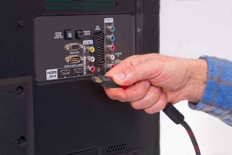 Hand halten HDMI-Kabel und verschiedene Anschlüsse am Fernseher