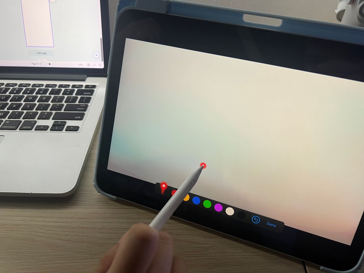 the iPad Gen 10th with a hand holding an Apple pen that using laser pointer feature