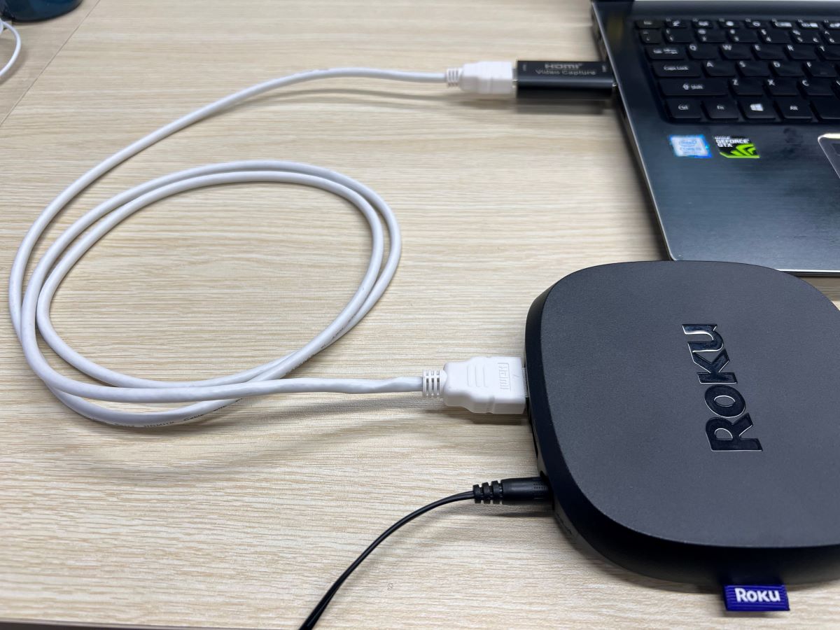 A white HDMI cable is connected to a capture card and a Roku Ultra