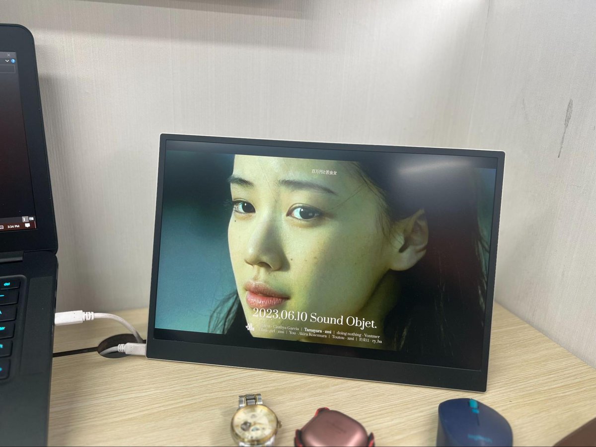 An LG portable monitor is on a wooden table with the image of a girl looks sad