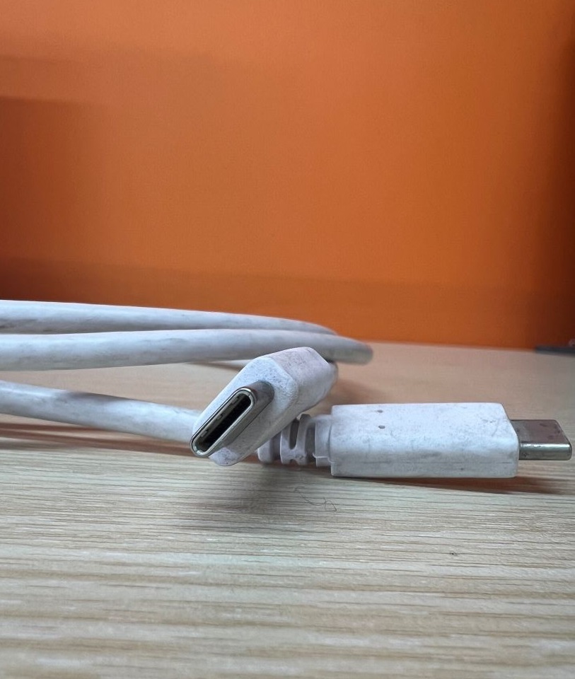 The DP Thunderbolt USB-C on a wooden table and an orange background