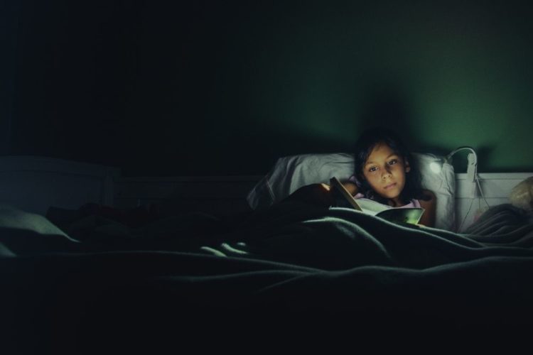 A girl reading in bed in the evening