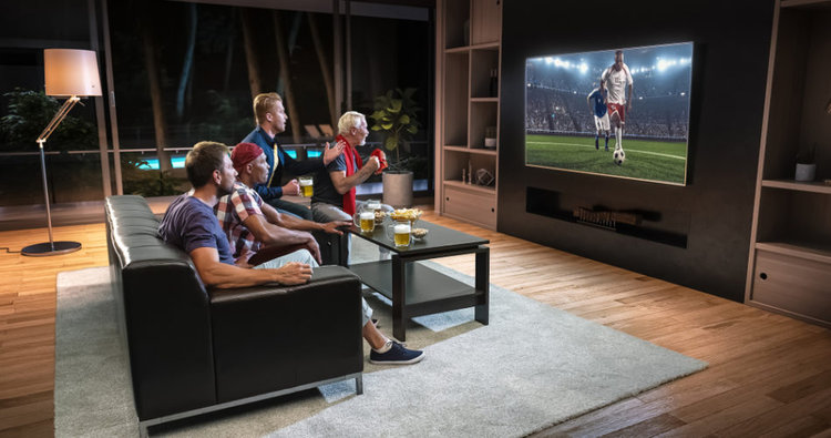 Eine Gruppe von Freunden schaut Fußball auf 4K TV