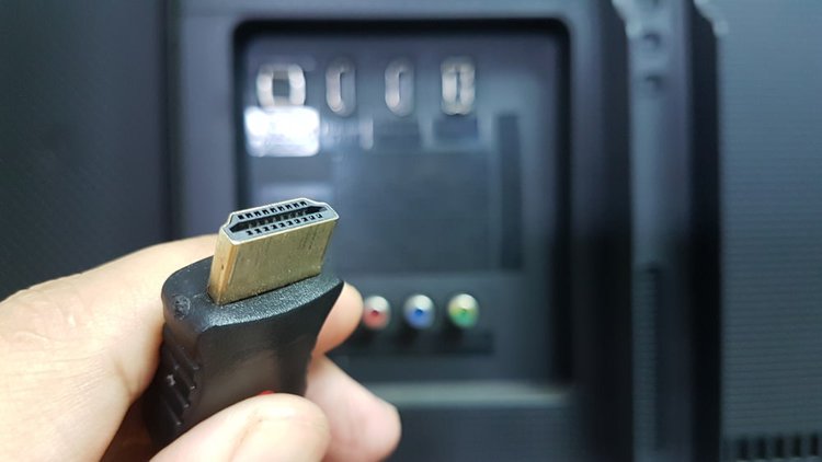 A hand holds a HDMI cable end