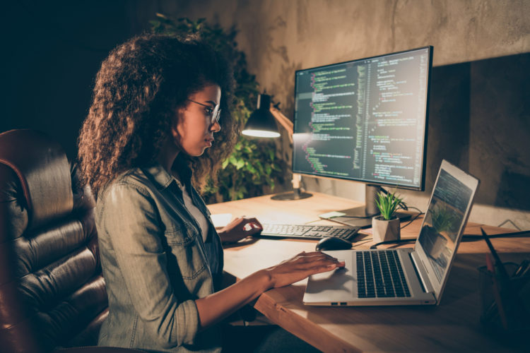 A woman using both laptop and monitor